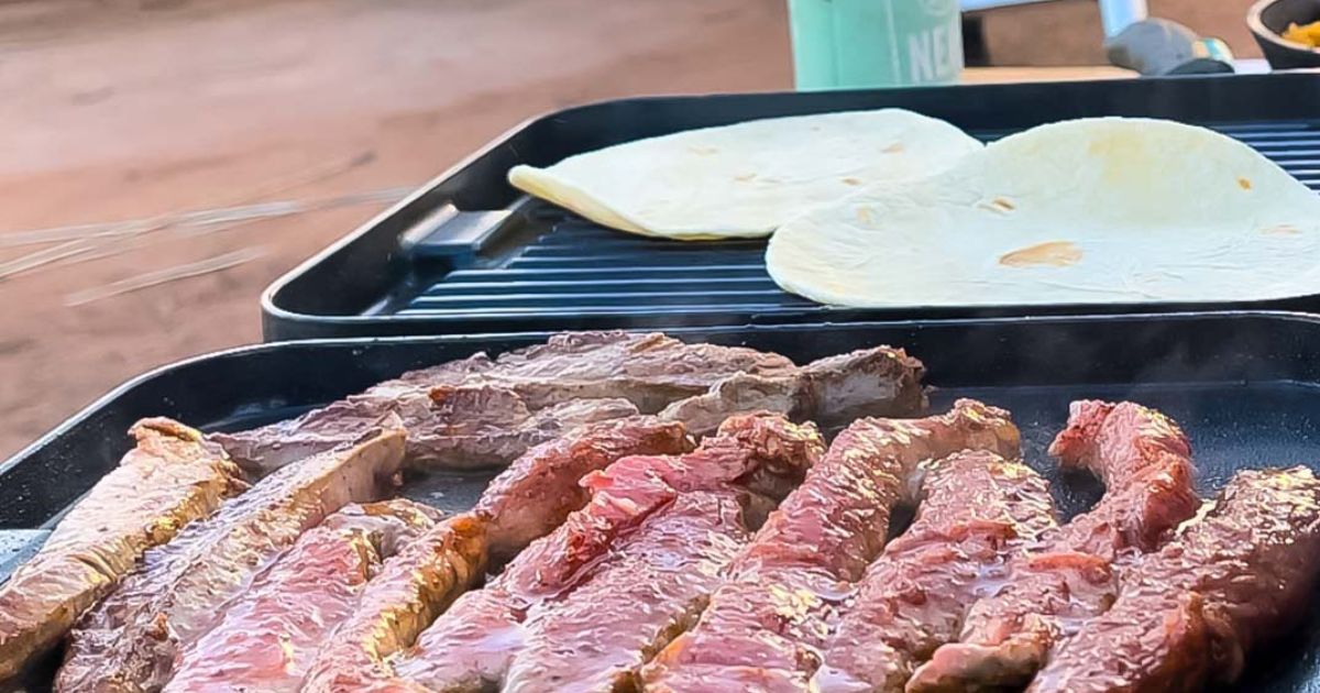 steak strips and tortillas cooking on outdoor grill at campsite